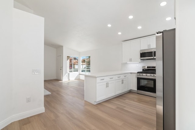 kitchen featuring appliances with stainless steel finishes, a peninsula, light countertops, light wood-type flooring, and white cabinetry