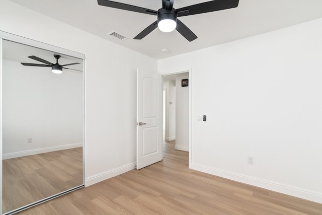 unfurnished bedroom featuring light wood finished floors, baseboards, visible vents, ceiling fan, and a closet