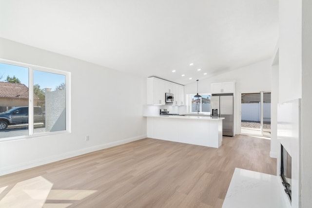 kitchen featuring decorative light fixtures, light countertops, appliances with stainless steel finishes, white cabinetry, and a peninsula