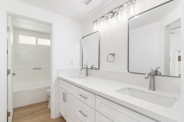 bathroom with double vanity, a sink, toilet, and wood finished floors