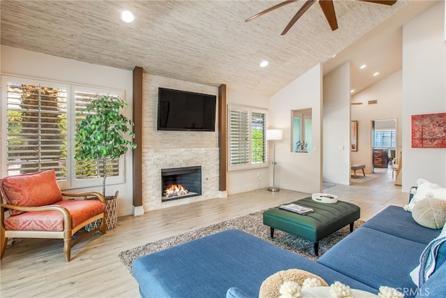 living area with light wood finished floors, a fireplace, high vaulted ceiling, and recessed lighting