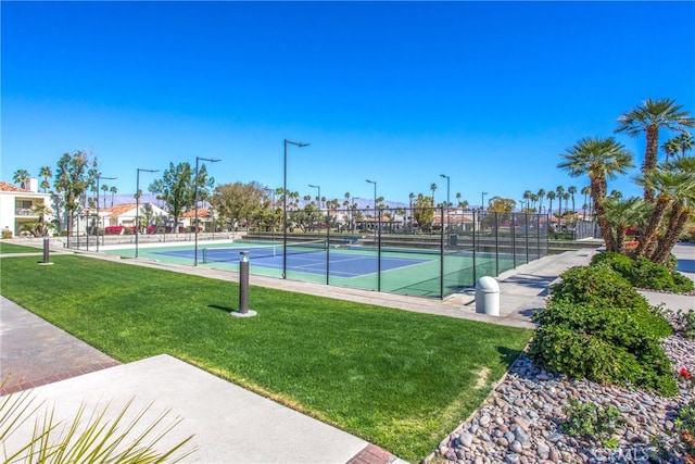 view of tennis court featuring fence and a yard