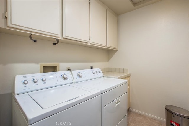 laundry room with light tile patterned floors, washing machine and dryer, cabinet space, and baseboards