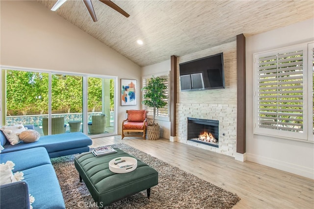 living area with ceiling fan, high vaulted ceiling, a fireplace, baseboards, and light wood finished floors