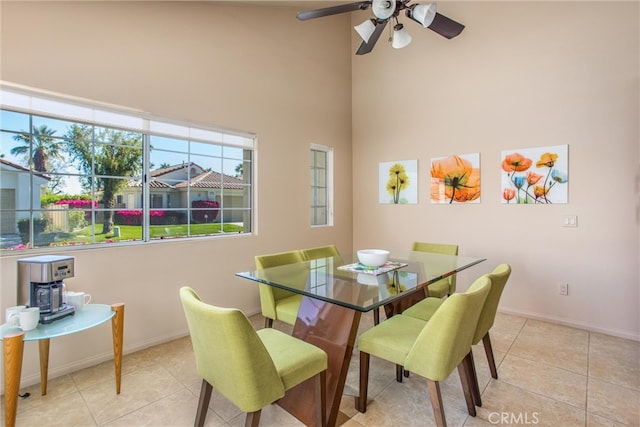 dining area featuring light tile patterned floors, a high ceiling, and baseboards