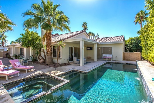 rear view of property with stucco siding, a pool with connected hot tub, a patio area, fence, and a tiled roof