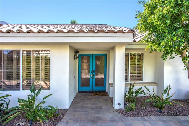 doorway to property featuring french doors, a tiled roof, and stucco siding