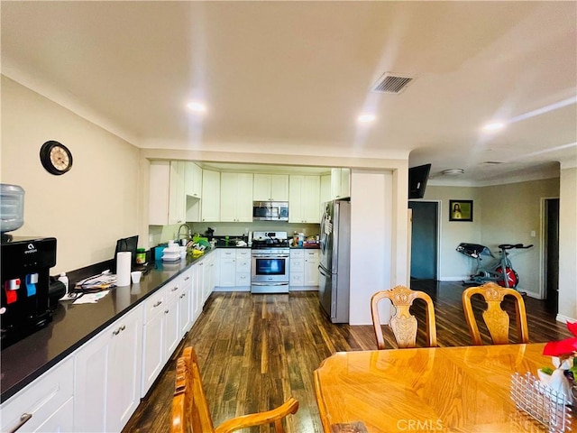 kitchen with appliances with stainless steel finishes, dark wood finished floors, visible vents, and white cabinetry