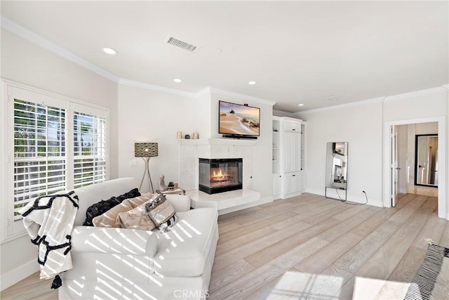 living room featuring visible vents, a premium fireplace, crown molding, light wood-style floors, and recessed lighting