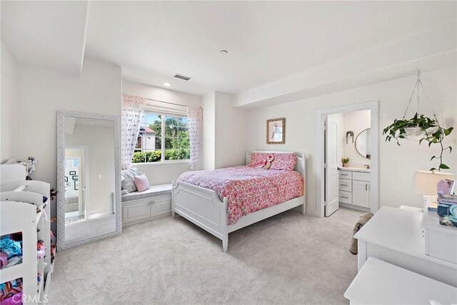 bedroom with ensuite bath, visible vents, and light colored carpet