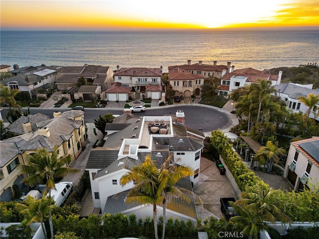 aerial view at dusk with a water view and a residential view