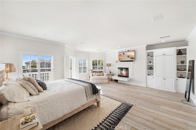 bedroom featuring a glass covered fireplace, multiple windows, light wood-style flooring, and recessed lighting