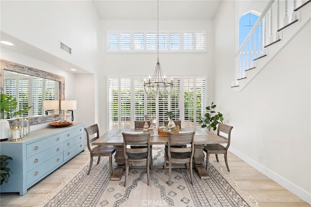 dining area featuring light wood-type flooring, plenty of natural light, baseboards, and a notable chandelier