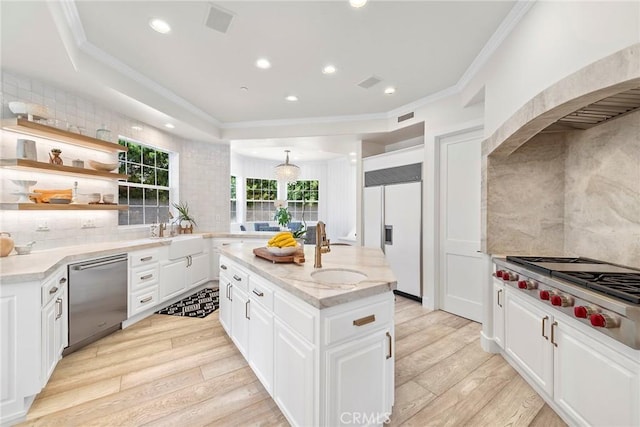 kitchen featuring appliances with stainless steel finishes, white cabinets, a kitchen island, and crown molding