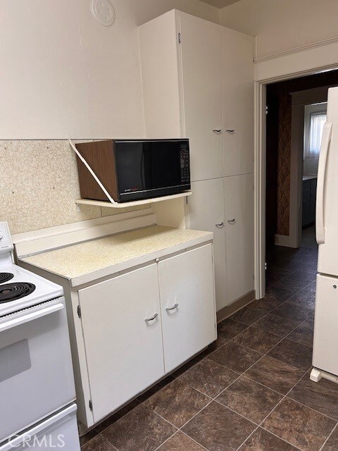 kitchen featuring white cabinets, white appliances, and light countertops