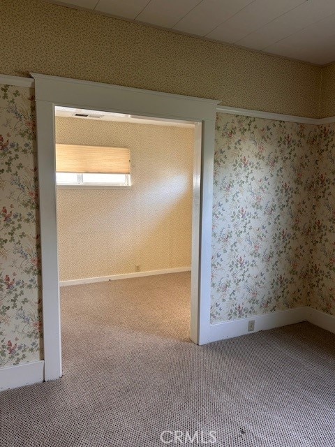 spare room with carpet flooring, baseboards, and wallpapered walls