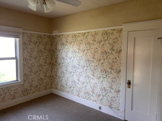 spare room with carpet, a healthy amount of sunlight, baseboards, and wallpapered walls