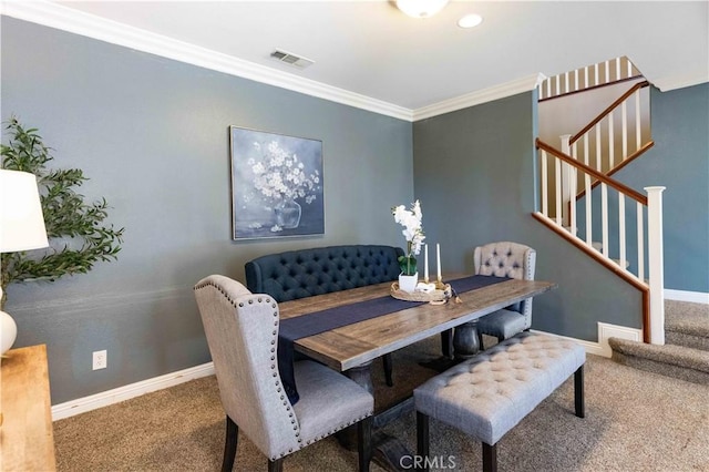 carpeted dining space with ornamental molding, visible vents, baseboards, and stairs