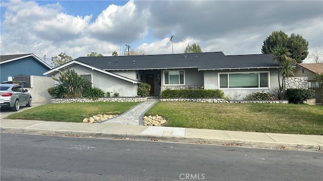 single story home with an attached garage, concrete driveway, a front yard, and stucco siding