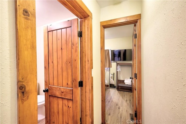 hallway with a textured wall and wood finished floors