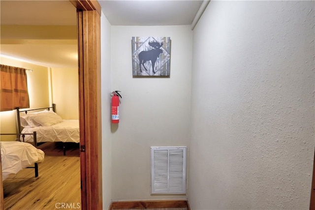 hallway featuring visible vents and wood finished floors