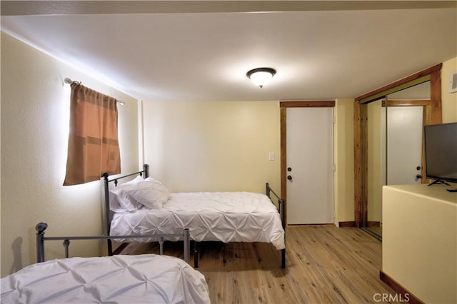 bedroom with a closet, baseboards, and light wood finished floors