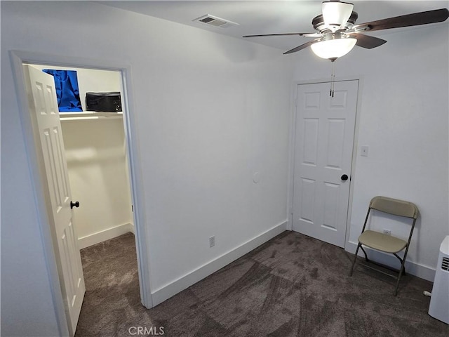 interior space featuring baseboards, visible vents, and dark carpet