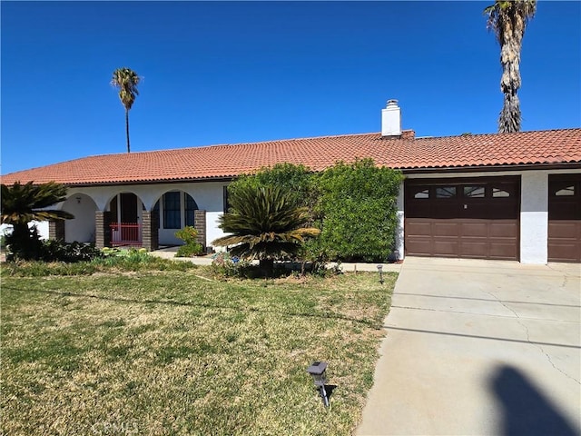 view of front of property featuring an attached garage, a tile roof, a front yard, and stucco siding