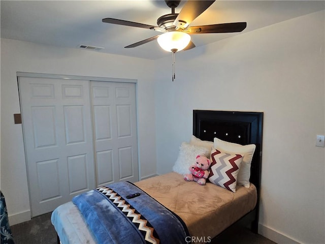 bedroom with a closet, visible vents, dark carpet, ceiling fan, and baseboards