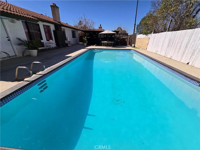 view of swimming pool featuring a patio, fence, and a fenced in pool