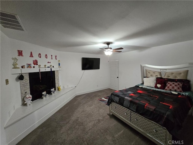 bedroom featuring baseboards, visible vents, a fireplace with raised hearth, ceiling fan, and carpet flooring