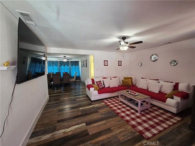 living room featuring dark wood-style floors, visible vents, baseboards, and a ceiling fan