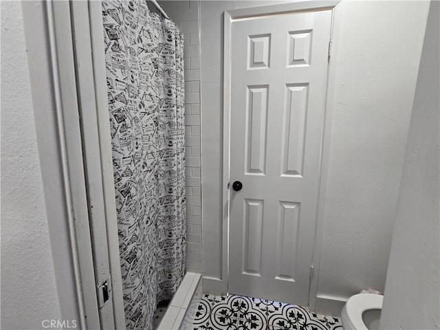 bathroom with a stall shower, toilet, and tile patterned floors