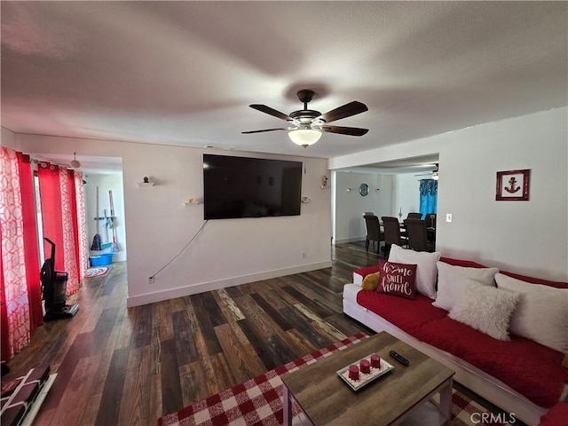 living room featuring dark wood-type flooring, a ceiling fan, and baseboards