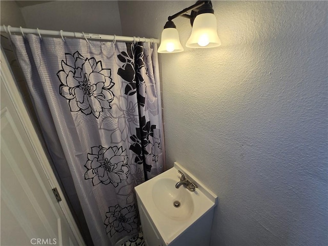 full bathroom with a textured wall and a sink