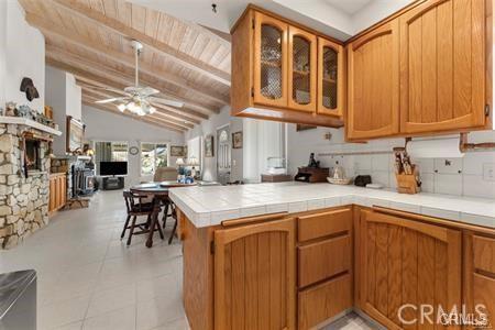 kitchen with a peninsula, tile counters, glass insert cabinets, and brown cabinets