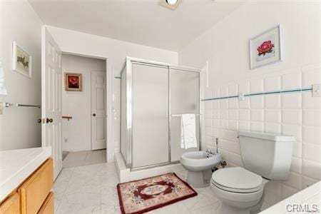 full bath featuring a stall shower, toilet, vanity, a bidet, and tile walls