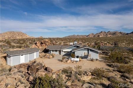 exterior space with an attached garage, dirt driveway, and a mountain view