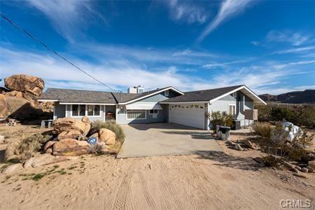 single story home with a garage and dirt driveway