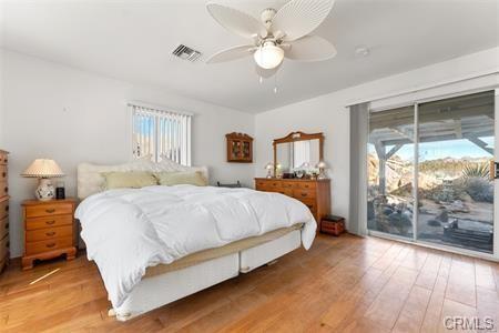 bedroom with access to outside, visible vents, ceiling fan, and wood finished floors