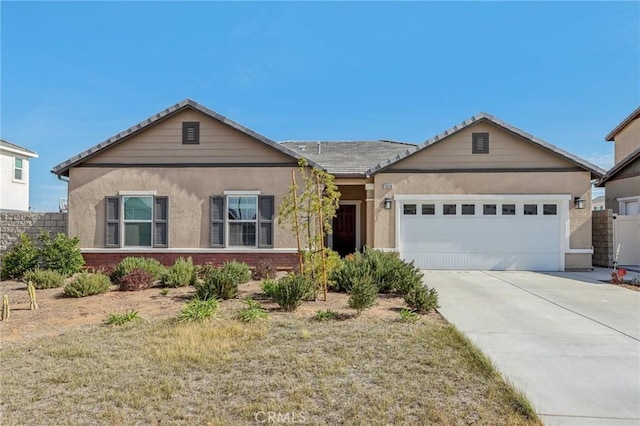 ranch-style house with a garage, brick siding, concrete driveway, and stucco siding