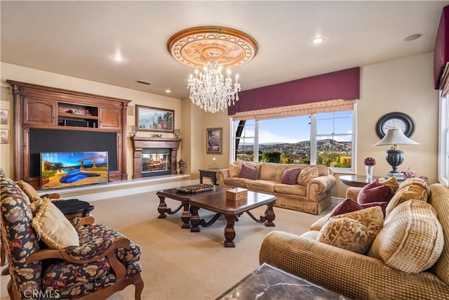 living area with recessed lighting, light colored carpet, visible vents, an inviting chandelier, and a glass covered fireplace