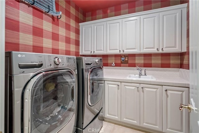 washroom with washer and clothes dryer, a sink, cabinet space, and wallpapered walls