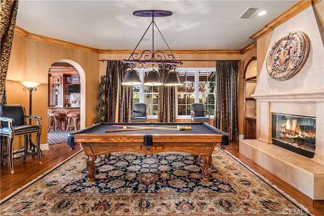 rec room featuring visible vents, a glass covered fireplace, wood finished floors, and ornamental molding