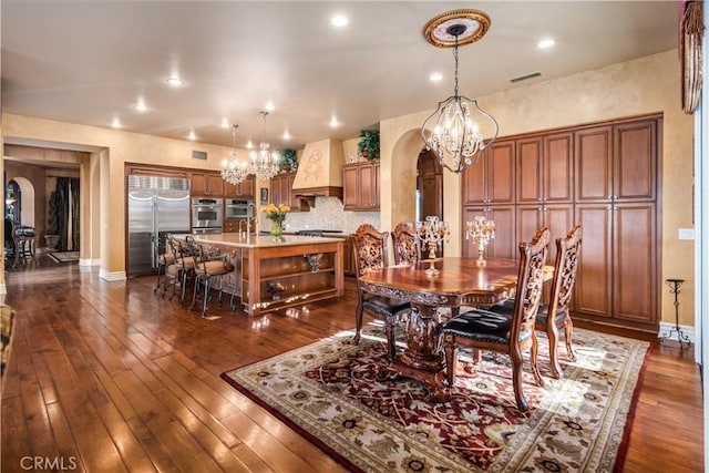 dining area featuring arched walkways, recessed lighting, dark wood-type flooring, visible vents, and baseboards