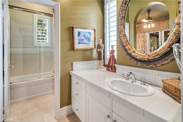 full bath featuring baseboards, ceiling fan, tile patterned floors, combined bath / shower with glass door, and vanity