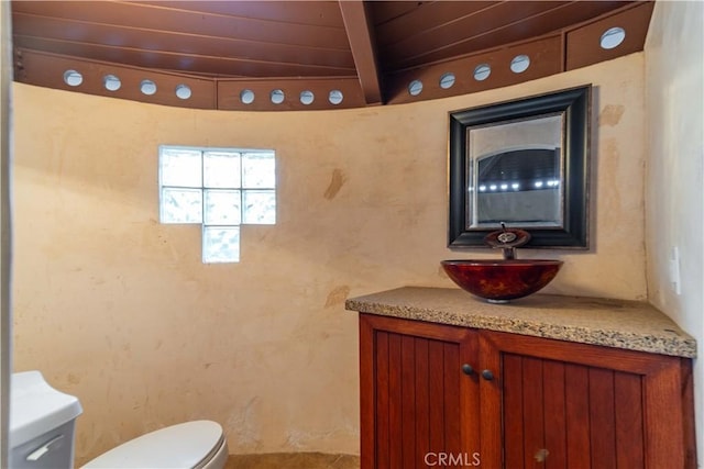 bathroom featuring toilet, wooden ceiling, vanity, and beam ceiling