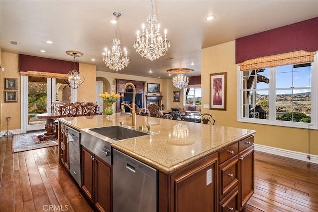 kitchen featuring dishwasher, an inviting chandelier, a kitchen island with sink, and pendant lighting