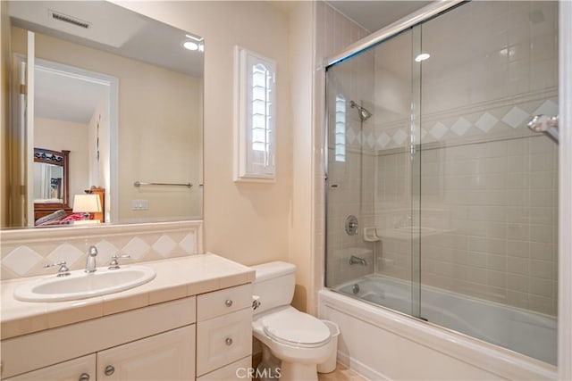 full bath with tasteful backsplash, visible vents, bath / shower combo with glass door, toilet, and vanity