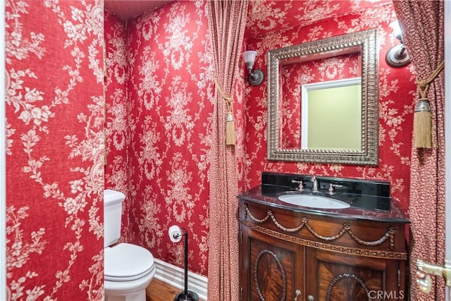 half bath featuring vanity and toilet